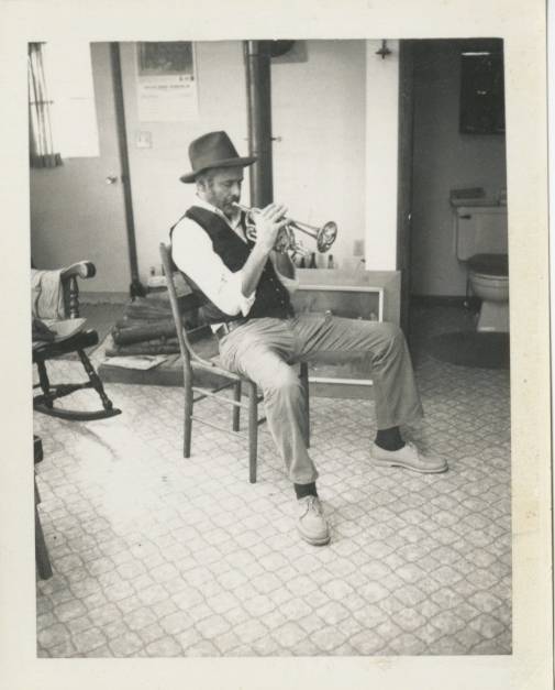 man playing trumpet while sitting on chair
